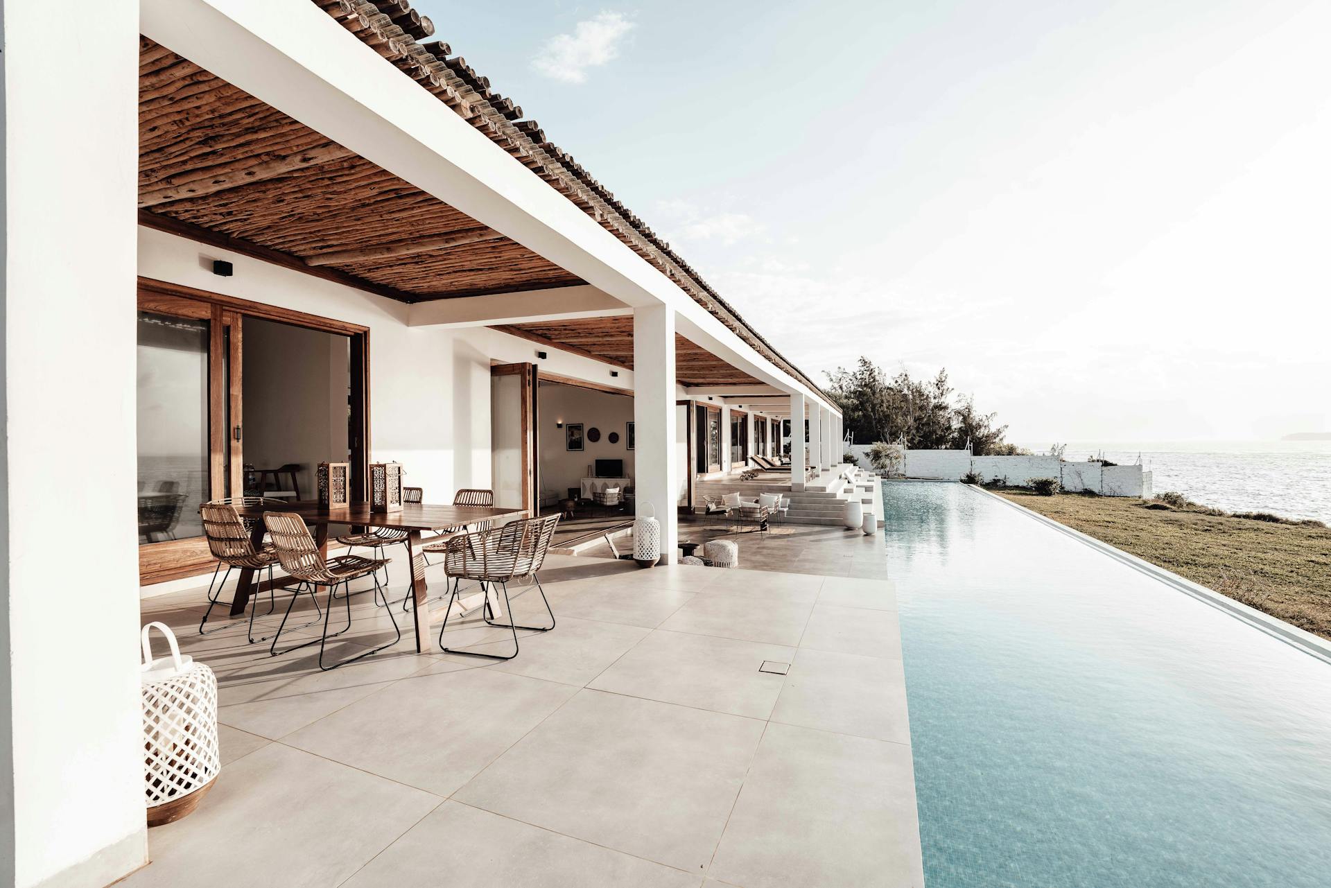 Libélula Group | About Libélula Group | Vacation Rentals &Amp; Expert Management Elegant Porch Featuring An Infinity Pool, Outdoor Dining Area, And Serene Lake Or Ocean View.